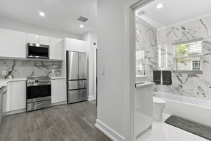 Una cucina moderna con elettrodomestici in acciaio inossidabile, uno schienale in marmo e un pavimento in legno.