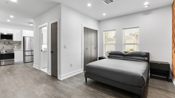 A modern bedroom with a large bed, a bedside table, and a wardrobe.