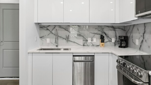 A modern kitchen with white cabinetry, a marble backsplash, stainless steel appliances, and a built-in oven. - Hyde Park 1/1 private residence 6 (Tampa)