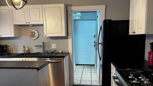 A kitchen with white cabinets, a black refrigerator, a stove, and a hanging light fixture. - 3-bedroom house in Southside Flats neighborhood of Pittsburgh. (Pittsburgh)