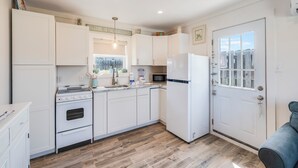 A compact kitchen with white cabinets, a built-in oven, a microwave, and a refrigerator. - Charming Port Aransas Cottage Near Beach Access (Port Aransas)