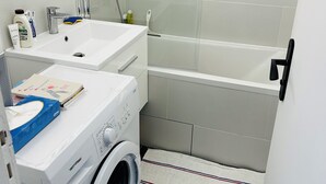 Un baño con lavadora, lavamanos y bañera.