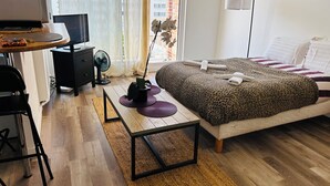 Un dormitorio moderno con cama, escritorio y ventilador de pie.