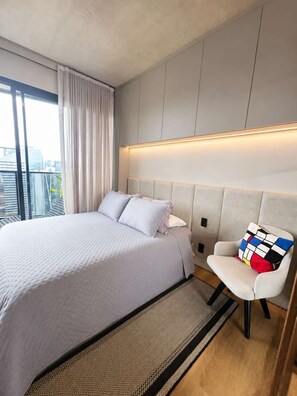 Ein modernes Hotelzimmer mit einem großen Bett, einem Sessel, einem Nachttisch und Blick auf die Stadt.