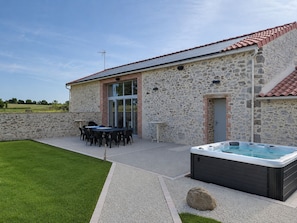 Ein Steinhaus mit Terrasse, Sitzgelegenheiten im Freien und einem Whirlpool.
