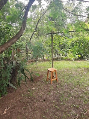 Un tamboret de fusta en un jardí amb arbres i una tanca.