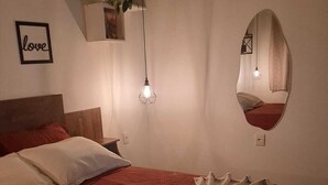 A bedroom with a bed, a bedside table, a hanging light fixture, a wall-mounted mirror, and a framed picture. - chacara temporada manu tobar brotas sp (Brotas)