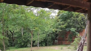 A hammock under a wooden structure with a grassy yard and trees in the background. - chacara temporada manu tobar brotas sp (Brotas)