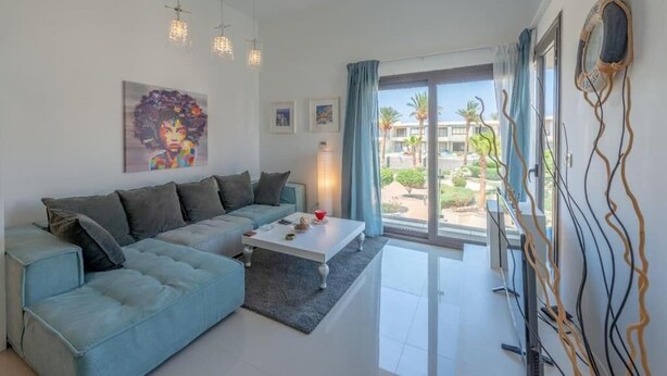 A modern living room with a sofa, coffee table, and artwork on the wall. - Gcribs apartment pool view (Hurghada)