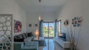 A modern living room with a sofa, TV, and artwork. - Gcribs apartment pool view (Hurghada)