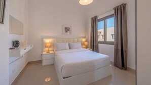 A hotel room with a bed, bedside lamps, a nightstand, a window with curtains, and a wall-mounted picture. - Gcribs apartment pool view (Hurghada)