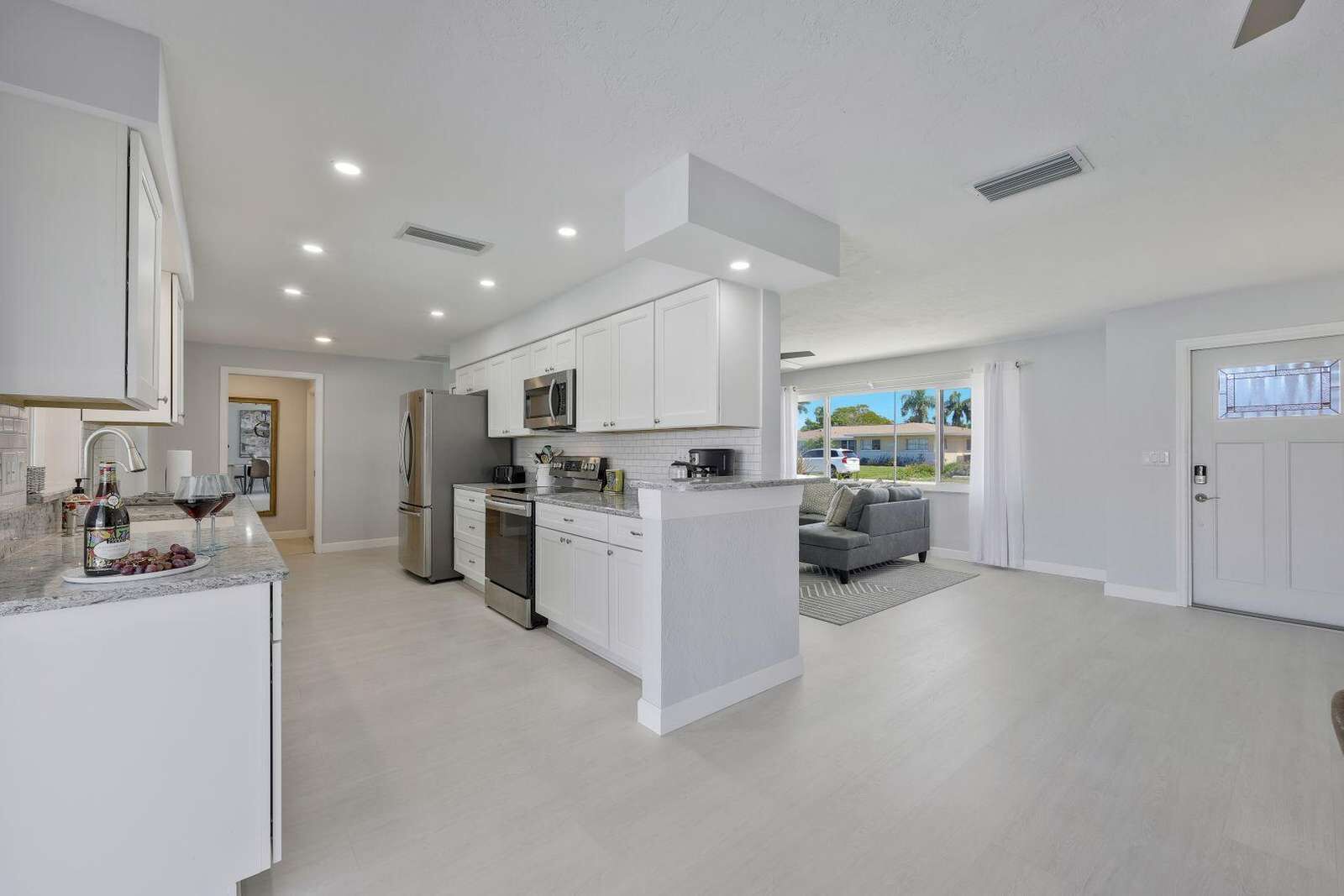A modern kitchen with white cabinetry, stainless steel appliances, and a central island.