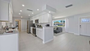 Cozinha moderna com armários brancos, eletrodomésticos de aço inoxidável e uma ilha central.
