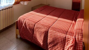 A bedroom with a bed, a TV, a mirror, and a window with curtains. - Maiella Experience - Downtown Apartment, Nestled in the Maiella Mountains (Campo di Giove)
