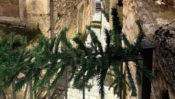 A narrow stone corridor with rustic wooden doors and a metal gate, leading to a view of a distant town. - Maiella Experience - Downtown Apartment, Nestled in the Maiella Mountains (Campo di Giove)