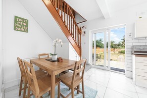 A dining area with a wooden table and chairs, a staircase, and a view of the backyard through glass doors. - Modern 4BR Home|Sleep 7|Free Parking|Self check in (Southend-on-Sea)