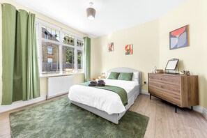 A bedroom with a bed, dresser, and artwork on the wall. - Modern 4BR Home|Sleep 7|Free Parking|Self check in (Southend-on-Sea)