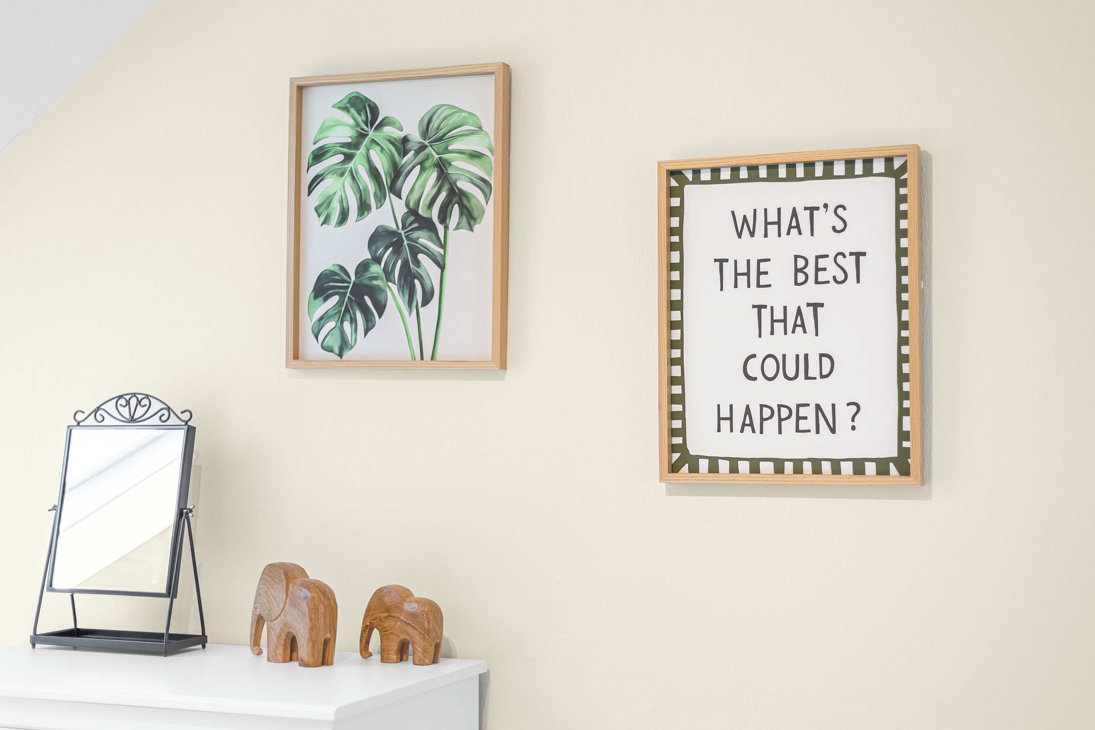 A wall with two framed items: a plant illustration and a motivational quote sign.
