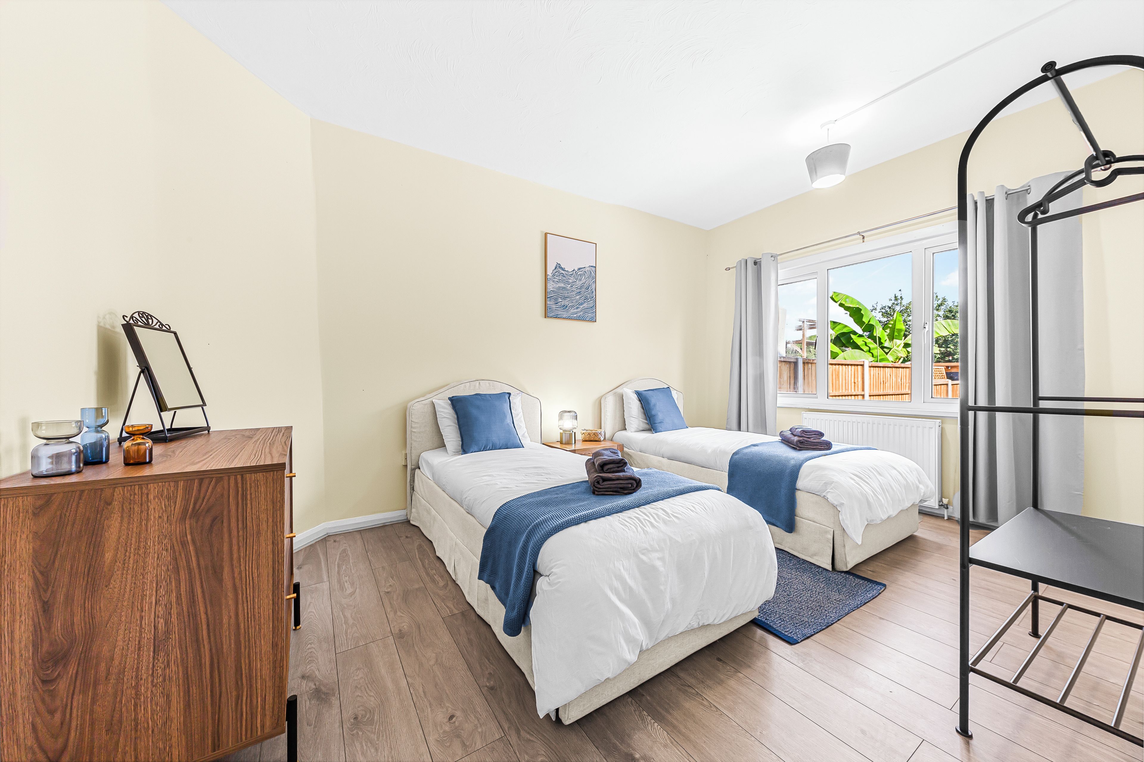 Un dormitorio con dos camas, un aparador de madera y una ventana con cortinas.