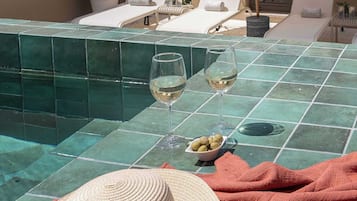 Escena junto a la piscina con sillas de descanso, un libro y un sombrero de paja.