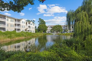 Ein Wohngebiet mit mehrstöckigen Gebäuden, einem Teich und üppiger Bepflanzung.
