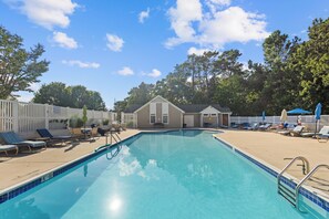 A swimming pool with lounge chairs and a small building in the background. - Blue Marlin Condo Rehoboth Beach 2BR/ 2BA (Rehoboth Beach)