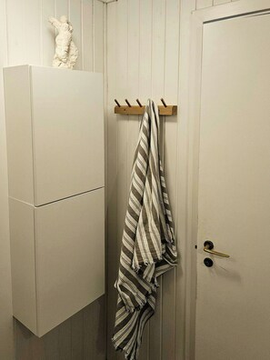 Ein Badezimmer mit einem weißen Schrank, einem Handtuchhalter mit einem gestreiften Handtuch und einer Tür mit Messinggriffen.