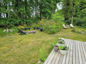 Eine Terrasse mit Topfpflanzen, einer Feuerstelle aus Steinen und Gartenmöbeln.