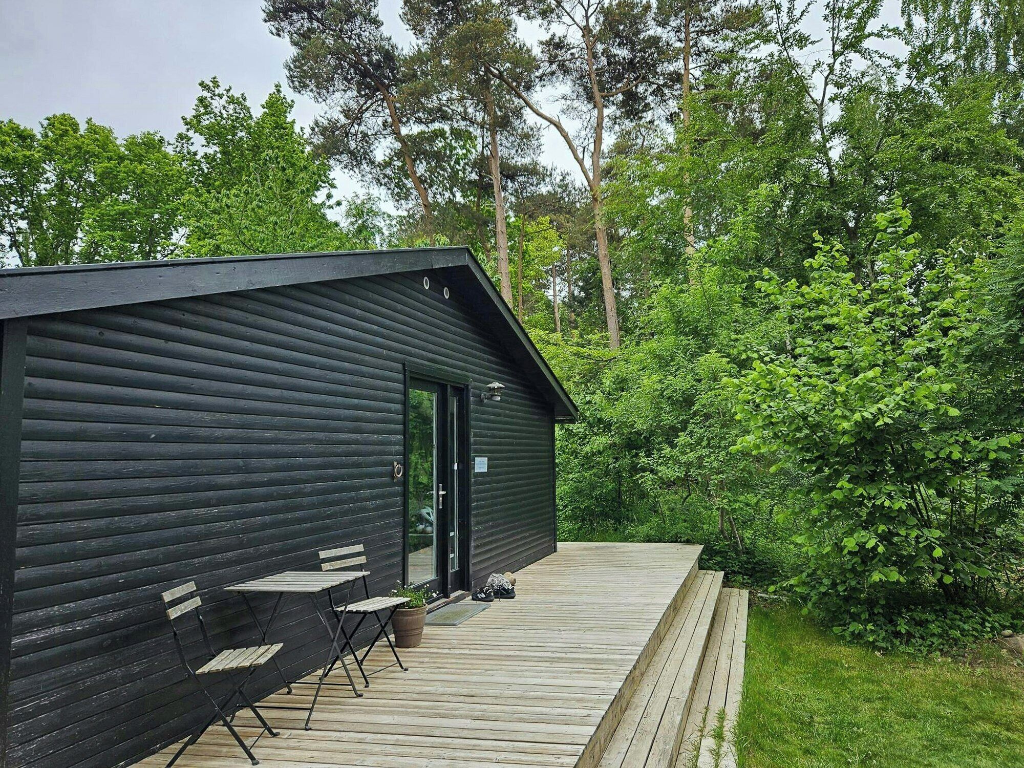 A cabin with a deck, a door, and a small outdoor seating area.