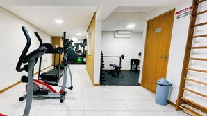 Un gimnasio con máquinas de cardio, equipo de levantamiento de pesas y un letrero que indica una sala de ejercicios.
