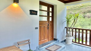 A wooden door with a sign, a bench, a potted plant, and a balcony with a railing. - BREZO APARTMENT, 10 MINUTES FROM CANGAS DEL NARCEA (Veigaipope)