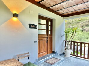 A wooden door with a sign, a bench, a potted plant, and a balcony with a railing. - BREZO APARTMENT, 10 MINUTES FROM CANGAS DEL NARCEA (Veigaipope)