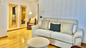 A modern living room with a sofa, a round coffee table, and a chandelier. - BREZO APARTMENT, 10 MINUTES FROM CANGAS DEL NARCEA (Veigaipope)