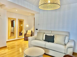 A modern living room with a sofa, a round coffee table, and a chandelier. - BREZO APARTMENT, 10 MINUTES FROM CANGAS DEL NARCEA (Veigaipope)