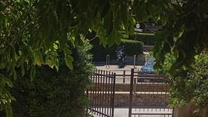 A paved pathway leading to a gated entrance, surrounded by lush greenery. - Casa Glicine Isola Del Giglio: Sea View, Private Terrace and Garden (Giglio Campese)
