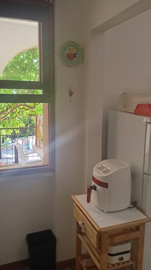A kitchen with a window, a small table with a white appliance, and a trash bin. - Casa Glicine Isola Del Giglio: Sea View, Private Terrace and Garden (Giglio Campese)