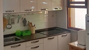 A kitchen with white cabinets, a black countertop, and a window. There are plates with designs on the wall above the cabinets. - Casa Glicine Isola Del Giglio: Sea View, Private Terrace and Garden (Giglio Campese)