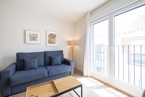 Ein modernes Wohnzimmer mit grauem Sofa, einem Holztisch und zwei gerahmten Kunstwerken an der Wand.