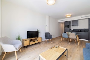 Una sala de estar moderna con televisión, asientos, comedor y cocina.