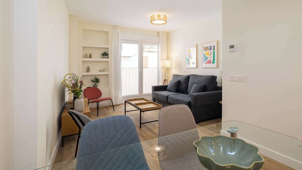 Een moderne woonkamer met een bank, stoelen, een salontafel en een glazen tafel.