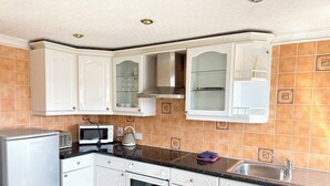 A kitchen with white cabinets, a microwave, a stove, and a sink. - Belgravia Holiday Apartments No 6 (Torquay)