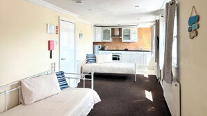 A bedroom with two beds, a kitchenette, and a bathroom. - Belgravia Holiday Apartments No 6 (Torquay)