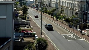A street lined with multi-story buildings, a designated bike lane, and a clear view of the ocean. - Belgravia Holiday Apartments No 6 (Torquay)
