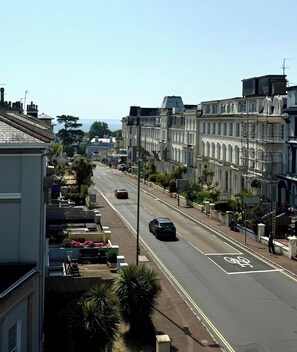 Eine Straße gesäumt von mehrstöckigen Gebäuden, mit einer ausgewiesenen Fahrradspur und freiem Blick auf das Meer.