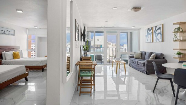Una habitación de hotel moderna con balcón, comedor y sala de estar.