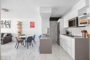 Eine moderne Küche mit weißen Schränken, einer eingebauten Mikrowelle und einem Edelstahl-Kühlschrank.