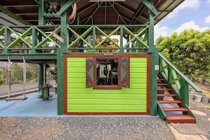 Un edificio verde con una escalera que lleva a un balcón, un columpio y una ventana pequeña.