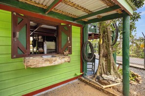 Eine rustikale Außenküche mit Holzauszug, Spüle und Fenster mit Holzklappläden.