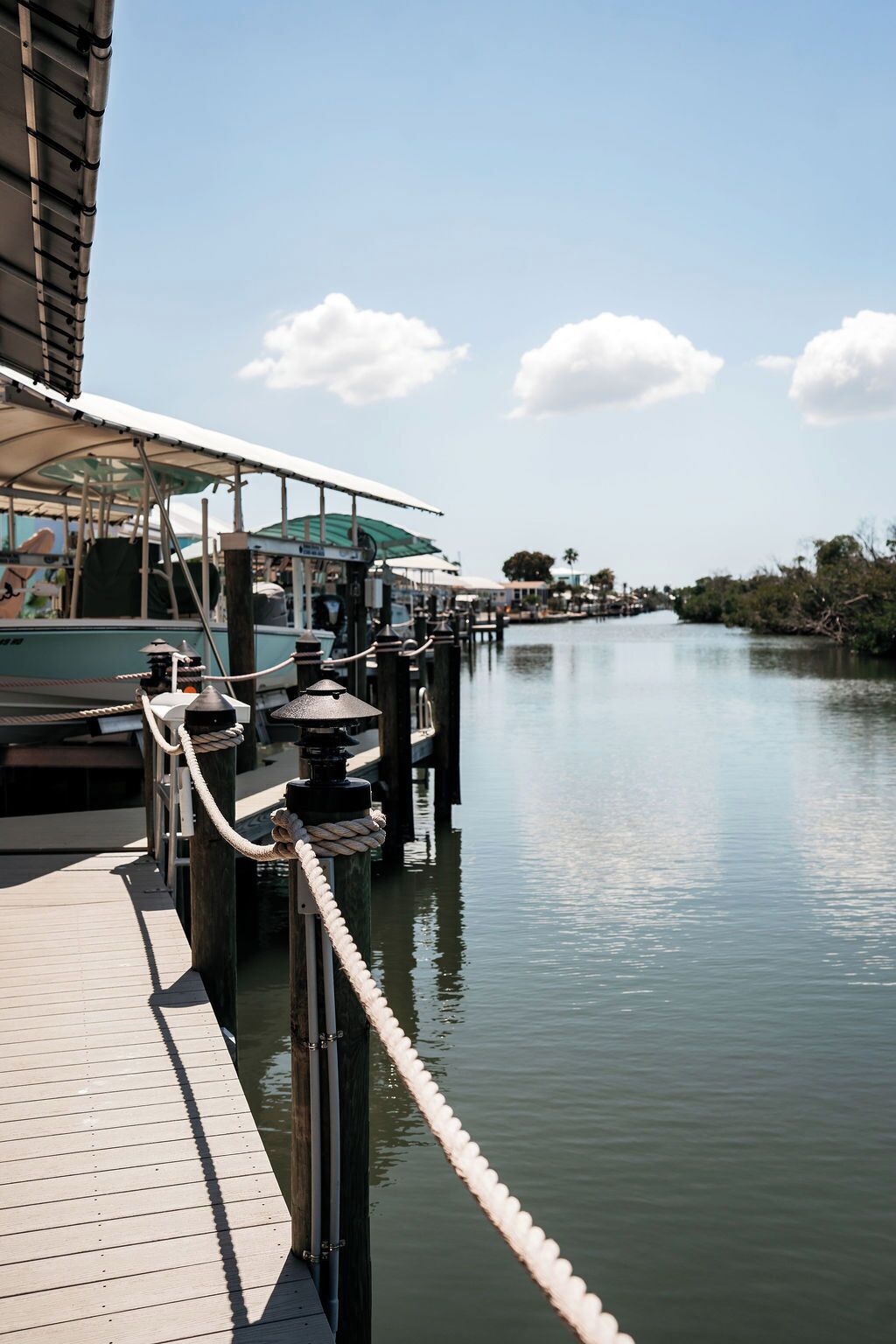 A dock with a wooden walkway, a covered seating area, and a calm water body.