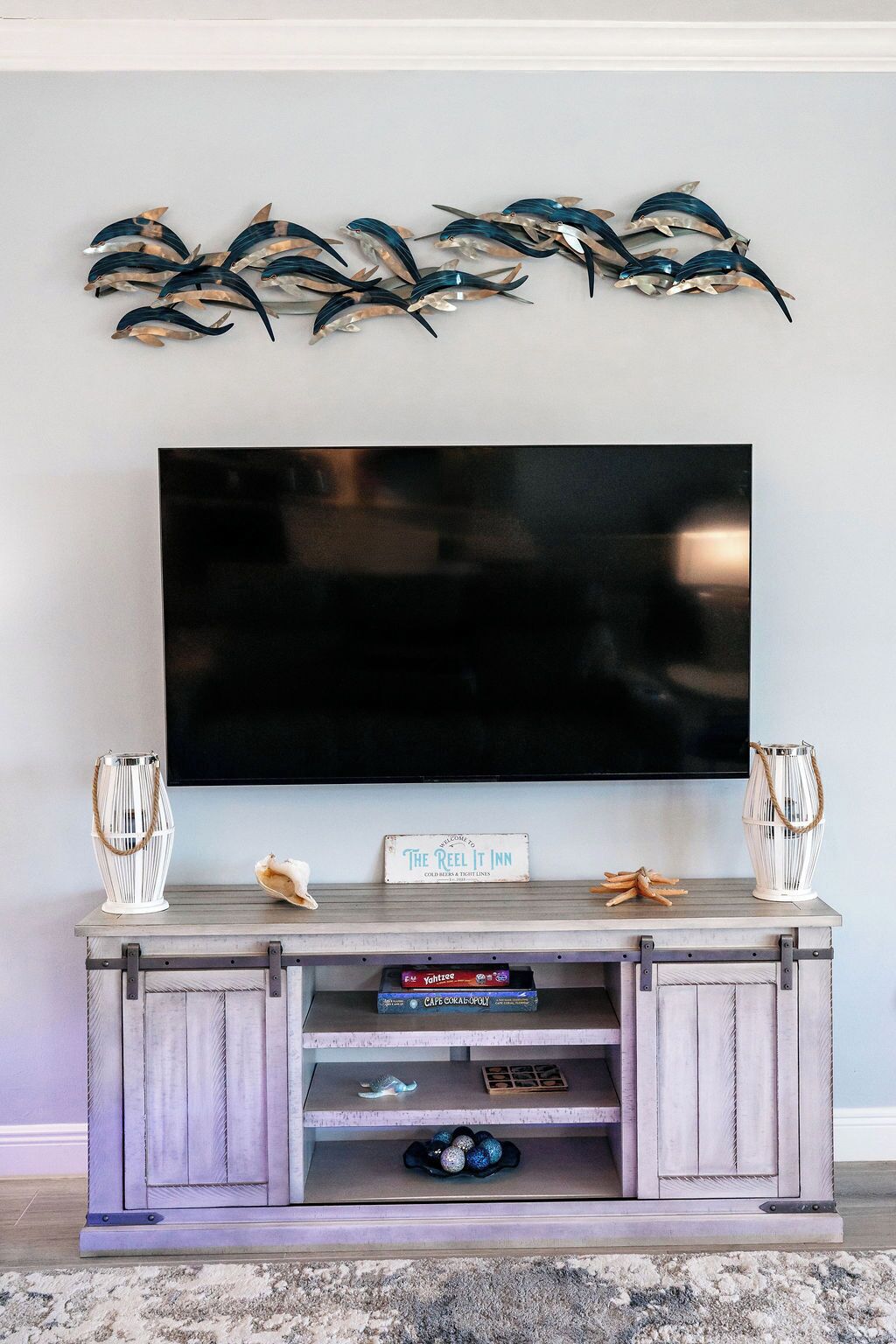 Ein Flachbildfernseher an der Wand über einem Holz-Entertainment-Center mit Dekoration und einem Schild.